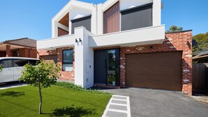 Ein modernes, zweistöckiges Haus mit Garage, gepflegtem Rasen und einem Baum im Vorgarten.
