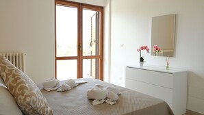 Ein Hotelzimmer mit Bett, Schminktisch, Spiegel und Fenster mit Blick auf Grünflächen.