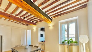 A dining area with a wooden ceiling, a window with plants, and a radiator. - Vetrina Roma - Stay in Luxury (Roma)