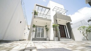 A modern two-story building with a flat roof, large windows, and a dark entrance door.