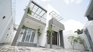 A modern two-story house with a balcony, a large window, and a door.