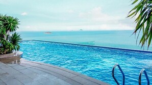 Une piscine avec vue sur l’océan et une petite île qui se profile à l’horizon.