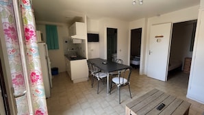 A compact kitchen with a dining area, a small wooden table, and a bench.