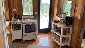 Ett kök med en spis, en ugn och en kaffebryggare på en hylla.