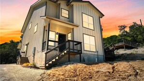 A two-story house with a balcony, a staircase, and a view of the surrounding landscape.