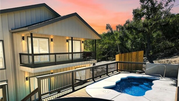 A two-story house with a deck, a hot tub, and a swimming pool.