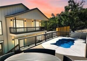 A two-story house with a deck, a hot tub, and a swimming pool.