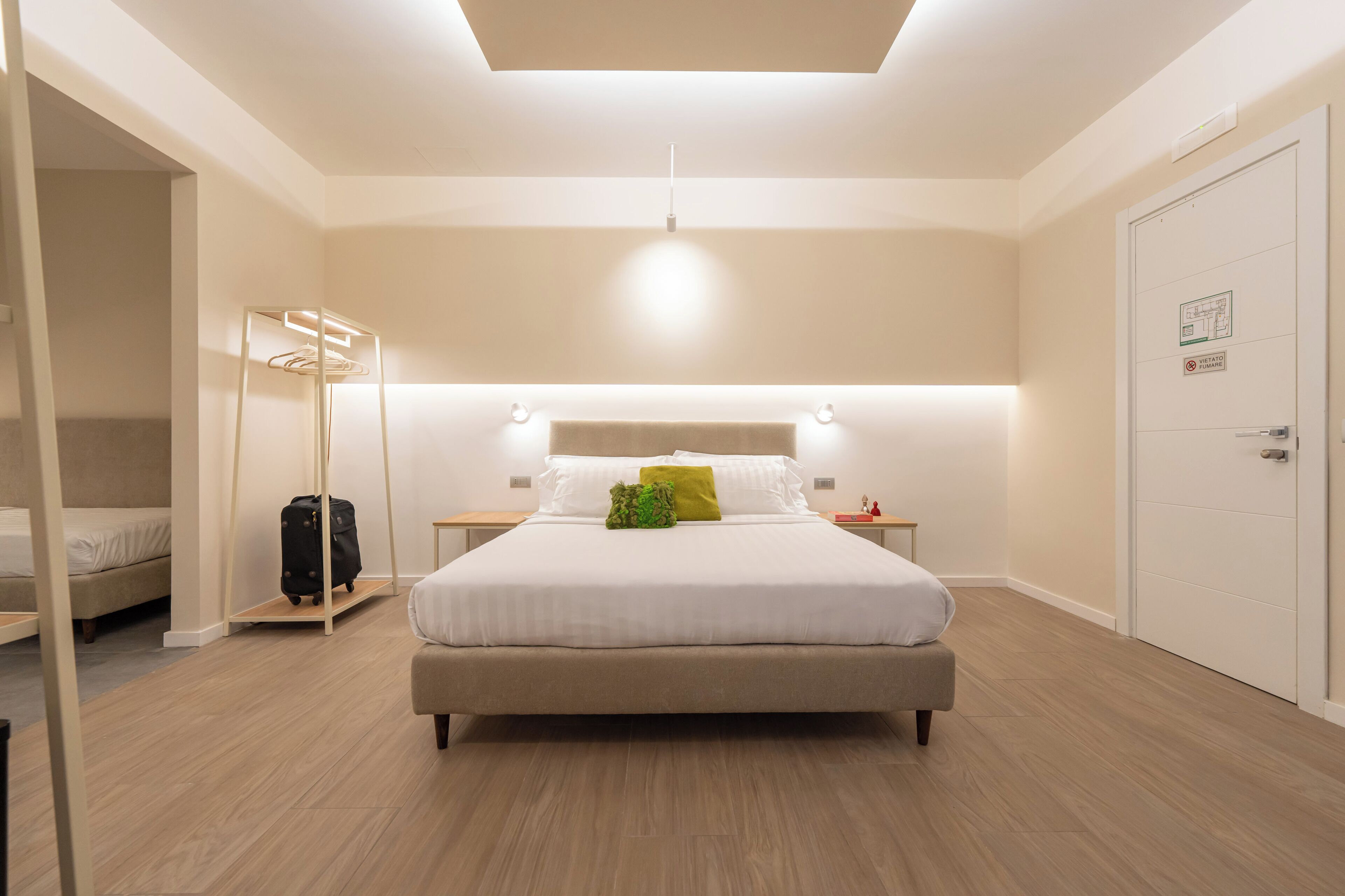 Une chambre d’hôtel avec un lit, des tables de chevet, une armoire et une valise.