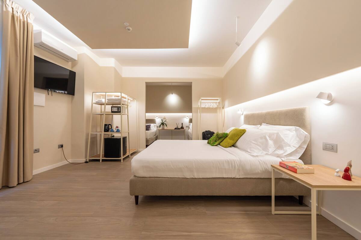 A modern hotel room with a large bed, bedside table, and a TV mounted on the wall.