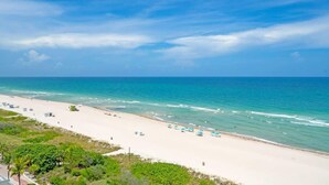A beach with white sand, clear blue water, and a few umbrellas. - Serena Beachfront 2 BRS Direct OceanView w Parking (Miami Beach)