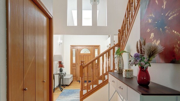 Un escalier en bois avec une rampe en verre, une porte en bois et un banc.