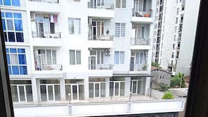 A balcony with a chair, a tiled floor, and a view of a multi-story building with balconies and windows. - sunshine (Batumi)
