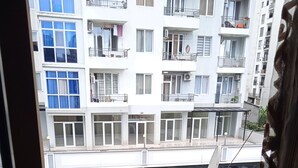 A balcony with a chair, overlooking a multi-story residential building with balconies and windows. - sunshine (Batumi)