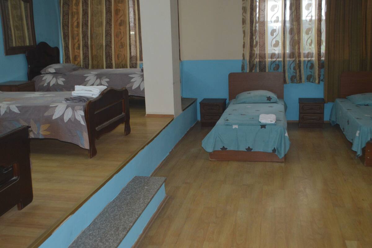 A hotel room with two single beds, a wooden dresser, and a small table.