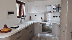 A compact kitchen with a microwave, oven, and a small sink. - Casa A&E - Panoramic Lake Orta Views (Prà della Marta)