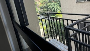 A balcony with a metal railing overlooking a cityscape with buildings and trees. - W Be Perdizes (São Paulo)