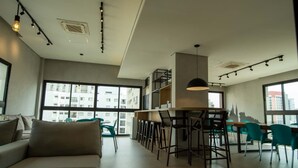 A modern interior with a sofa, bar area, and large windows. - W Be Perdizes (São Paulo)