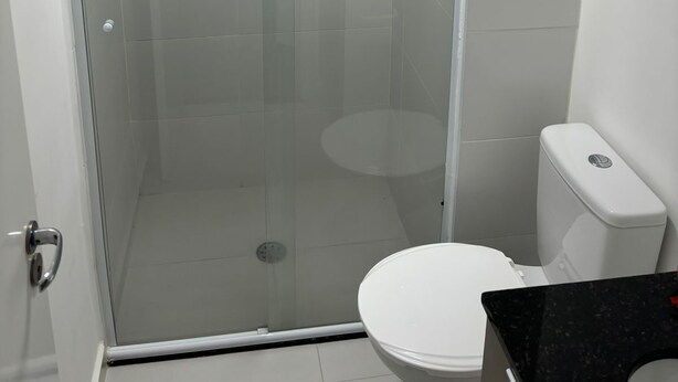 A modern bathroom with a glass-enclosed shower, a white toilet, and a black countertop. - W Be Perdizes (São Paulo)
