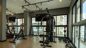 A gym with cardio machines, weightlifting equipment, and a large window with a city view. - W Be Perdizes (São Paulo)