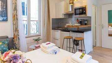A modern hotel room with a kitchenette, a dining area, and a balcony.