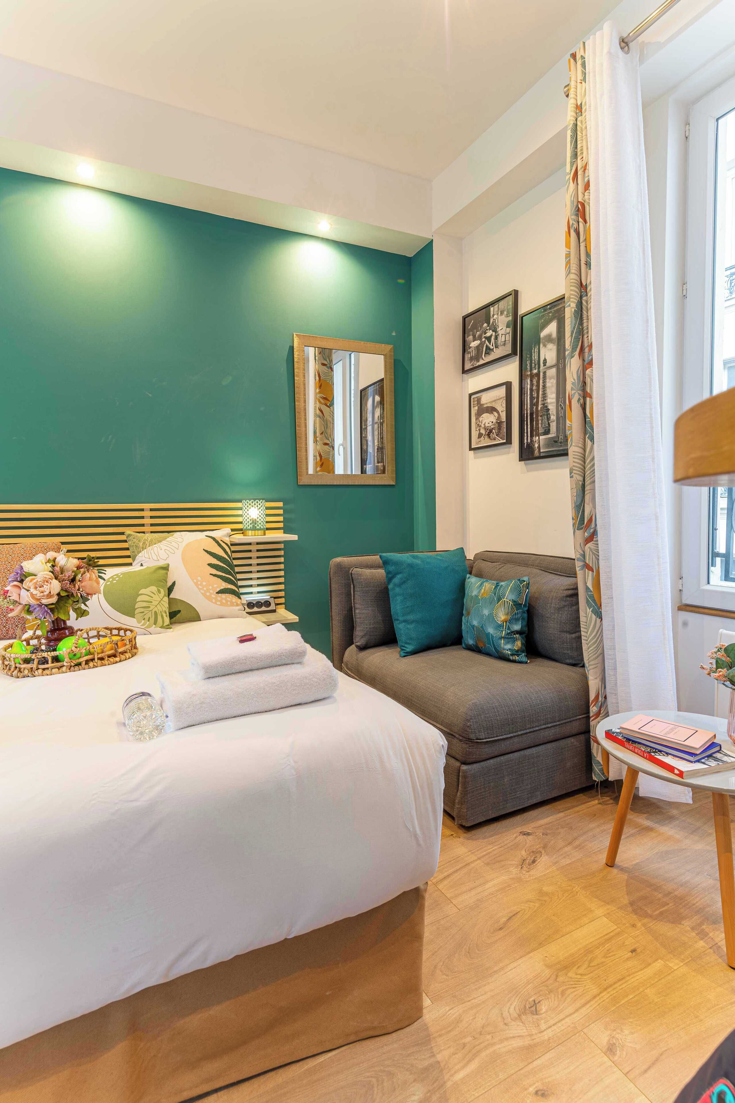 Une chambre à coucher avec un lit, un canapé, une petite table et un miroir.