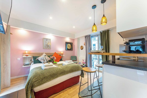 A modern hotel room with a bed, a small kitchen area, and a dining table. - Résidence Paris 58 BEAUREGARD (Paris)