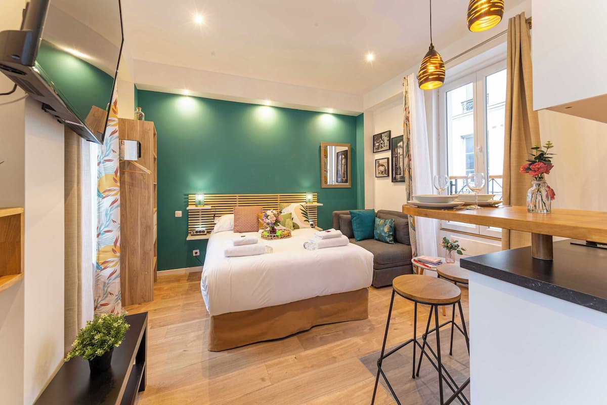 Un dormitorio moderno con una cama grande, un pequeño rincón de descanso y una kitchenette.