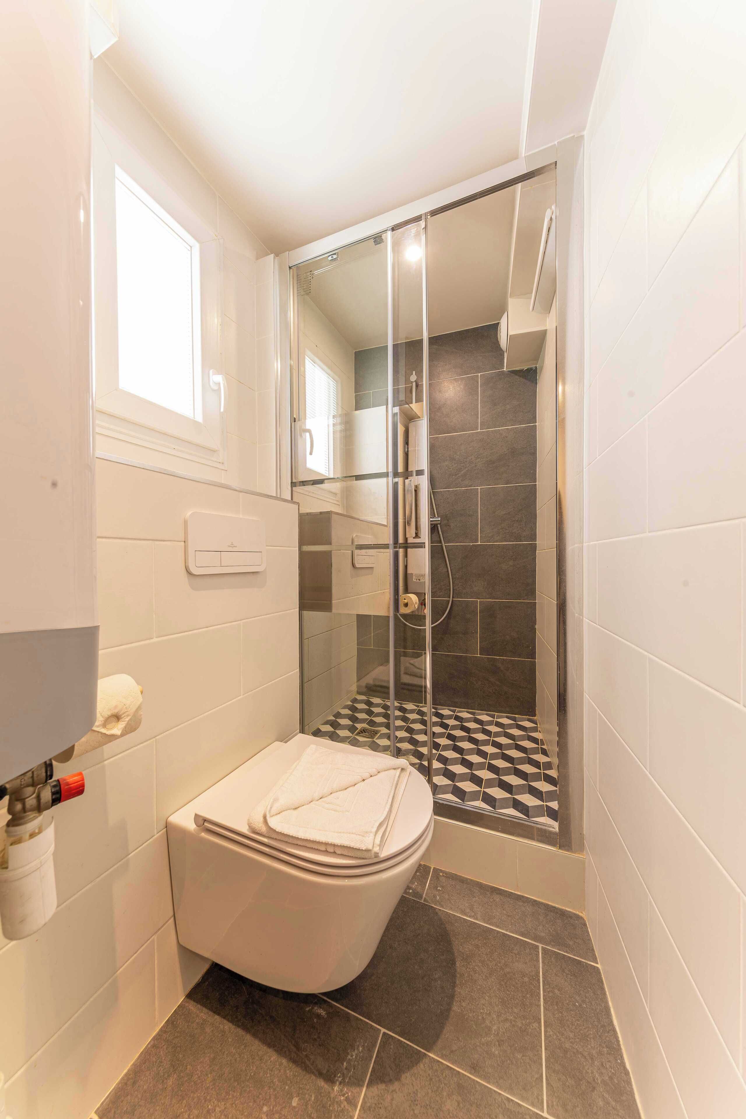 Un baño con inodoro, ducha con puerta de cristal y suelo a cuadros.