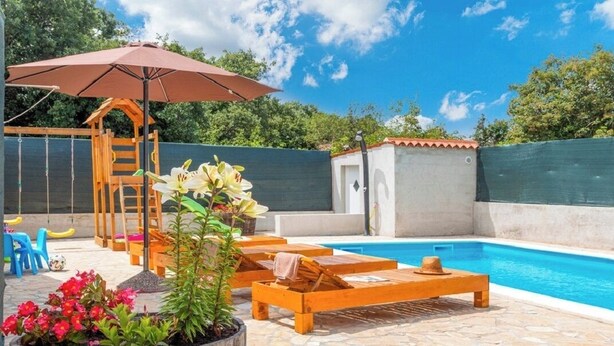 A backyard with a swimming pool, wooden lounge chairs, a wooden playset, and potted plants.