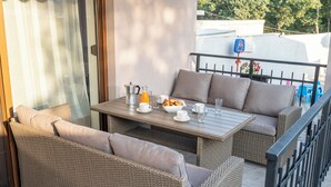 A balcony with wicker furniture, a table set with breakfast items, and a view of the outside.