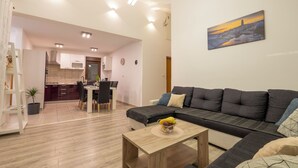 A modern living room with a sectional sofa, a coffee table with fruit, and a painting on the wall.