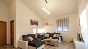 A modern living room with a sectional sofa, a coffee table with fruit, and a TV on a white console.
