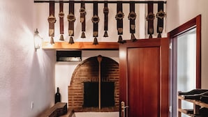 A narrow hallway with a brick oven, a wine rack, and a wooden door.