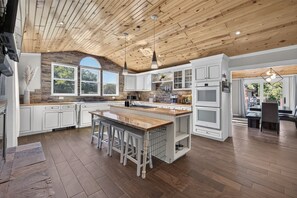 A spacious kitchen with a large island, white cabinetry, and a wooden ceiling. - Sleeps 10/Batting Cage/Theater! (Westfield)