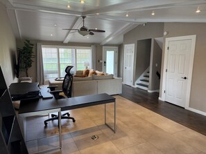 A spacious living area with a sofa, a desk, and a ceiling fan.