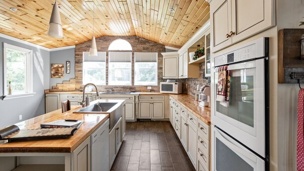 A kitchen with wooden ceiling beams, a stone arch window, white cabinets, and a built-in oven. - Sleeps 10/Batting Cage/Theater! (Westfield)