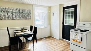 A compact kitchen with a dining table, chairs, a stove, and a window. - Spacious 2BR House with Netflix, BBQ, and Patio Near City Centre (Peterborough)