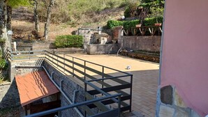Une cour avec un mur en pierre, un banc en bois et un ballon de volley-ball.