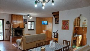 Un salon chaleureux avec une cheminée, des meubles en bois, une table à manger et un coin cuisine.