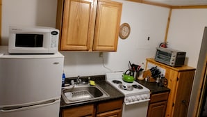 Una cocina compacta con armarios de madera, un microondas, una estufa y un tostador.
