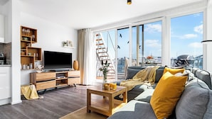En moderne stue med sofa, sofabord, fjernsyn og træhylder.
