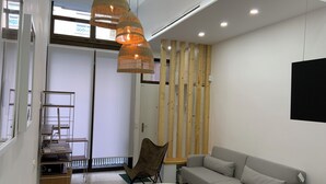 A modern interior with a sofa, a chair, a white table, and a hanging light fixture.
