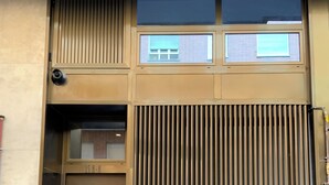 A building entrance with a large metal door, a small window, and a vertical metal panel.