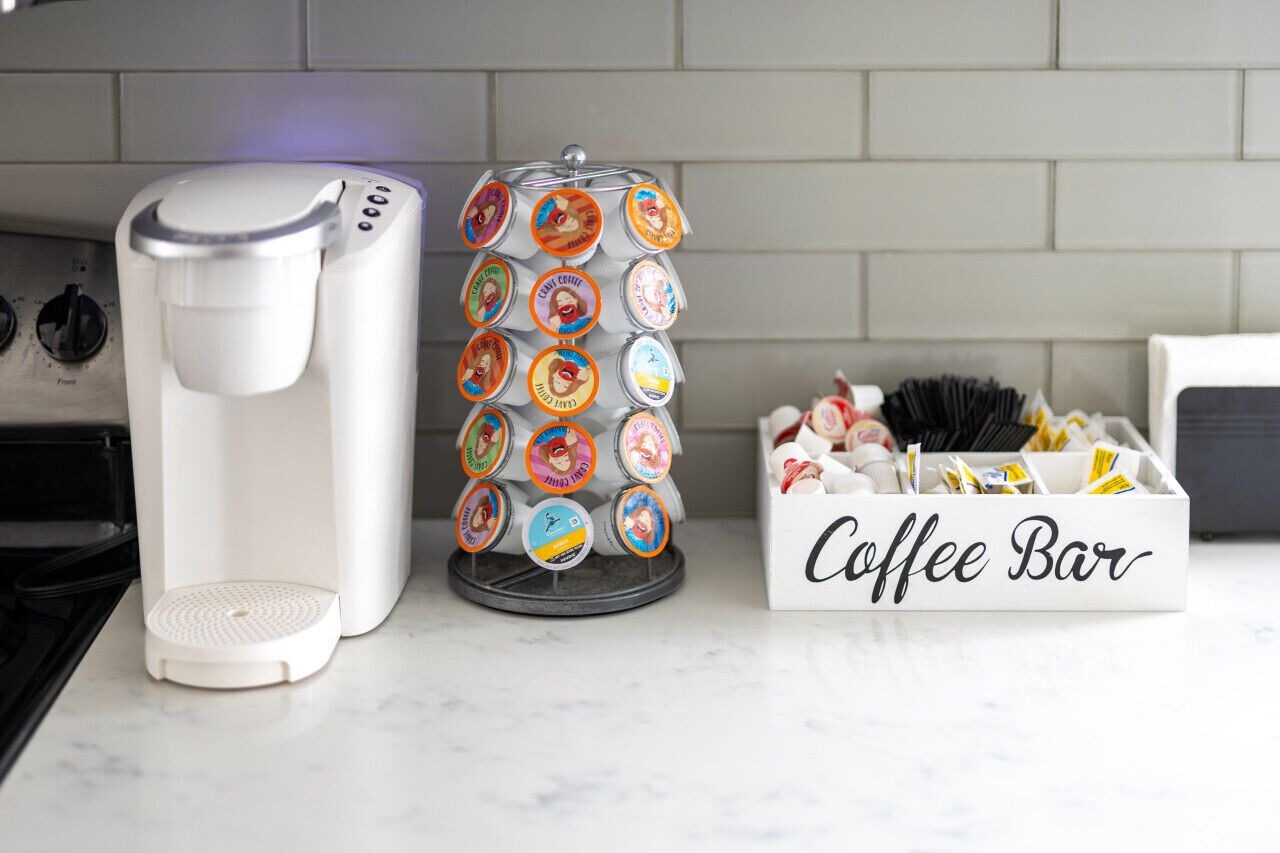 Een koffiezetapparaat, een koffiepadapparaat en een doos met koffiebarbonen op een aanrecht.