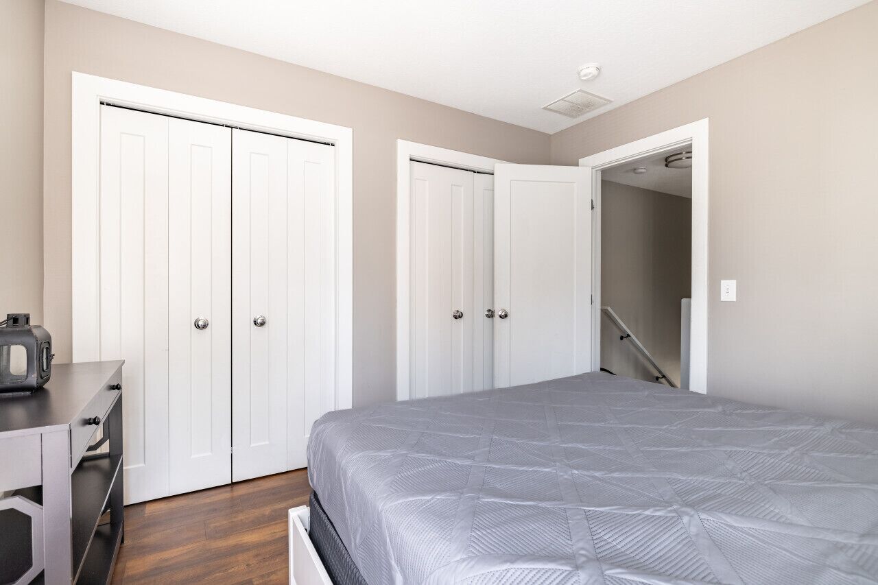 Une chambre à coucher avec un lit, un bureau et deux armoires blanches.