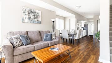 A spacious living room with a sofa, coffee table, and a painting on the wall.
