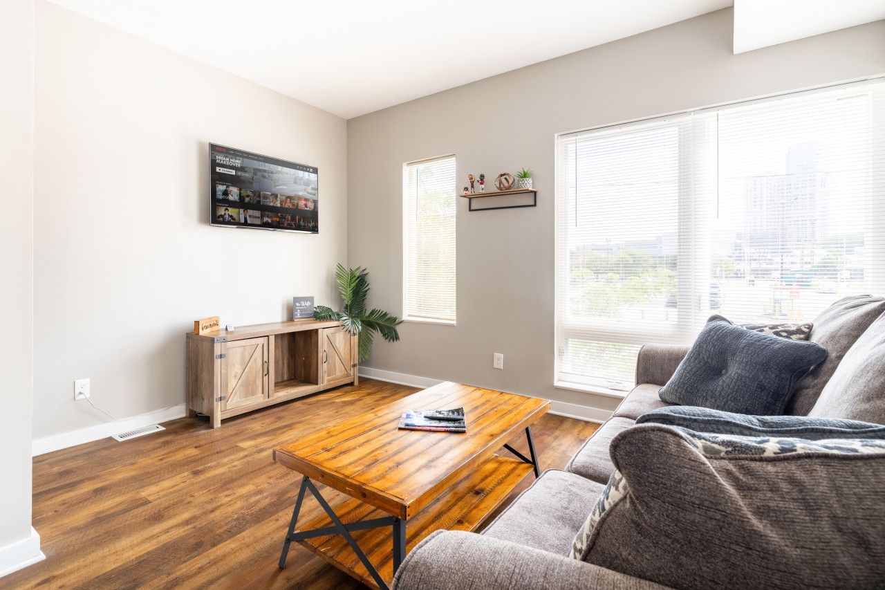 Una sala de estar con una mesa de centro de madera, un sofá gris y un mueble bajo con una planta.