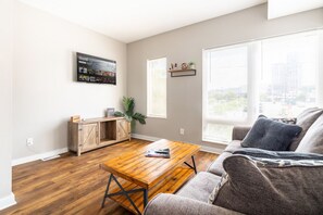 Una sala de estar con una mesa de centro de madera, un sofá gris y un mueble bajo con una planta.