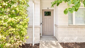 A building entrance with a number 9 door, a small window, and a tree to the left.