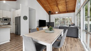 A modern kitchen with a dining area, a large window, and a built-in fireplace. - Walk2Everything (Anglesea)